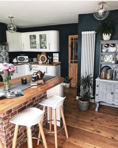 a kitchen with wooden floors and white cabinets, two bar stools next to the counter