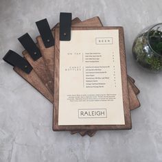 four wooden cutting boards with black handles on top of a table next to a plant