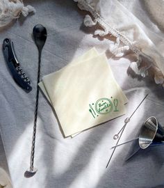 an assortment of sewing tools are laying on a tablecloth with some paper and scissors