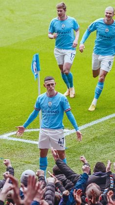 two soccer players are walking off the field with their hands in the air as they celebrate