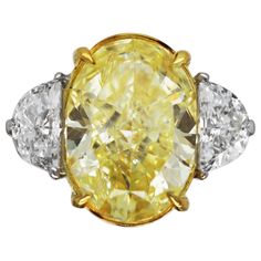 Three Stone Engagement Ring with GIA certified 5.40 carat Fancy Yellow Oval Cut Diamond center stone and two half moon side stones (0.92 TCW). Natural fancy yellow oval cut diamond with VS1 clarity set on 18k yellow gold and platinum. A perfectly proportioned 3 stone engagement ring featuring a richly colored, GIA certified, fancy yellow diamond. Fashioned into a brilliant oval cut, the pairing of half moon side stones fits seamlessly against the center stone. The side stones are E colored, with VS1 clarity and their combined weight is 0.92 carat. The setting, a mix of 18k yellow gold and platinum, is designed to emphasize the color of the center stone whilst offering a more modern look. As fancy colored diamonds are often cut to retain color, the open basket setting allows as much "fire” Half Moon Side Stones, 3 Stone Engagement Ring, 3 Stone Engagement Rings, Three Stone Engagement Ring, Fancy Yellow Diamond, Stone Engagement Ring, Three Stone Engagement, Three Stone Engagement Rings, Oval Cut Diamond