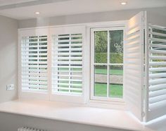 an empty room with white shutters on the windows