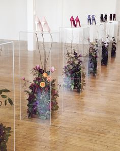 several clear vases with flowers and plants in them on the floor next to each other