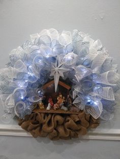 a nativity wreath hanging on the wall with light up decorations and lights around it