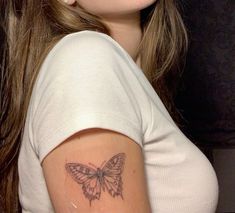 a woman with a butterfly tattoo on her arm and shoulder is looking at the camera