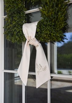 a pair of wreaths are hung on the front door with a white ribbon tied around it