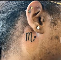 a man with a tattoo on his ear and behind the ear is a zodiac sign