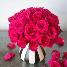 a black and white vase filled with pink roses on top of a gray countertop