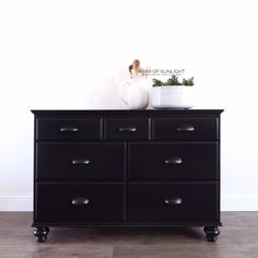 a black dresser with two white vases on top