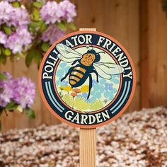 a wooden sign with a bee sitting on it's side in front of purple flowers