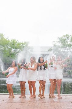 a group of women standing next to each other in front of a fountain