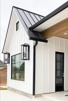 a white house with two black doors and a metal roof on the front of it