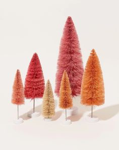 five different colored fake trees in white vases