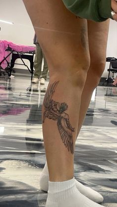 a person with a bird tattoo on their leg and legs, standing in the middle of a room