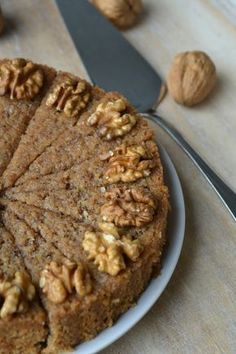 a cake with walnuts on top is sitting on a plate next to a knife