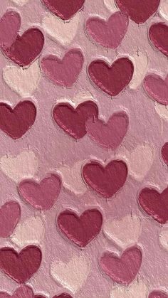 some pink and red hearts painted on the side of a piece of paper with watercolor paint