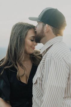 a man and woman standing next to each other in front of the ocean with their eyes closed