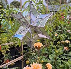 a garden filled with lots of flowers and plants next to a metal star shaped object