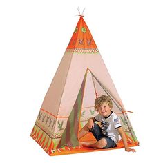 a young boy sitting in front of a teepee tent