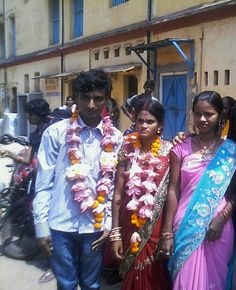 three women and one man are standing in front of a building with flowers on it