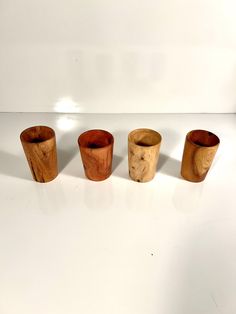 four wooden cups lined up on a white surface with one empty cup in the middle