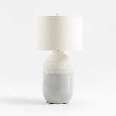 a white and grey table lamp with a white shade on the top, sitting in front of a white background