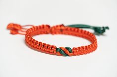 an orange and green rope bracelet on a white background