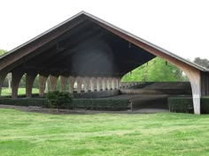 an outdoor pavilion with grass and trees in the background