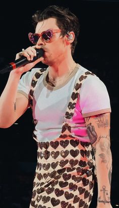 a man with tattoos and glasses on holding a microphone