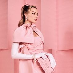 a woman in a pink dress and white gloves is posing for the camera with her hand on her hip