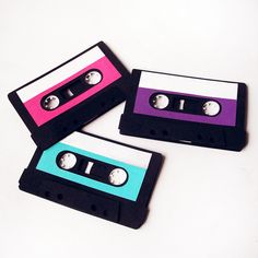 three black and pink cassettes are sitting next to each other on a white surface