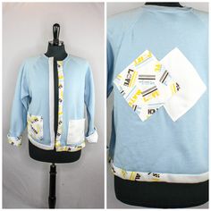 "Vintage 1970s Lee open front sweatshirt cardigan with tennis theme. 50% cotton, 50% polyester in light blue. Raglan sleeves. Fold up cuffs. Two patch pockets on the front. Trim, pockets and back patch details are all his half solid white and half tennis themed print. The print is black, blue, and yellow stripes and text that say \"LOVE\", \"MATCH\" and \"SET\". The label sizes this as a US women's XL.  Maker - Lee Condition - Some light pilling on the material. One small stain on the right shoulder, see photo.  Measurements -  Shoulders - 18\" (46cm) Length - 23\" (58cm) Sleeves - 16\" (41cm) inside edge, 19\" (48cm) outside edge 20% orders of 3 or more items! Use the code - MULTIORDER - at check out Free domestic shipping on all orders over $35 13-5" Sweatshirt Cardigan, Yellow Stripes, Label Sizes, Vintage 1970s, Raglan Sleeve, Matching Sets, Sweatshirts Women, Black Blue, Sweat Shirt