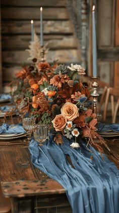 the table is set with candles, flowers and blue cloths on top of it