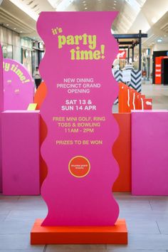 a pink sign sitting in the middle of a mall floor with other items on display