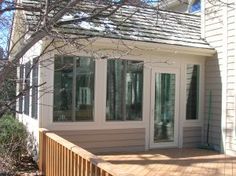 a house that has some windows on the side of it and a wooden deck in front of it