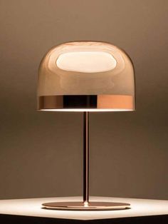 a table lamp that is sitting on top of a white surface and has a round light in the middle