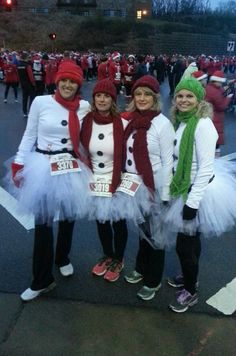 three women dressed up as snowmen in the middle of a street with other people