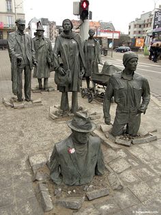 a group of statues sitting on the side of a road next to a traffic light