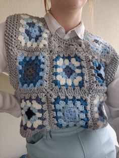 a woman is wearing a crocheted granny granny's sweater with flowers on it