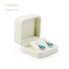 a pair of earrings in a white box on a white background with the words learning box written below it