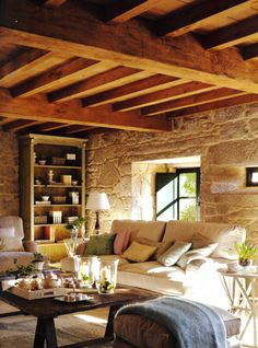 a living room filled with furniture and a stone wall covered in bookshelves next to a window