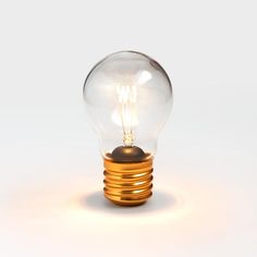 an illuminated light bulb sitting on top of a white surface with no one around it