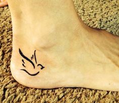 a small tattoo on the foot of a person with a bird flying over it's head