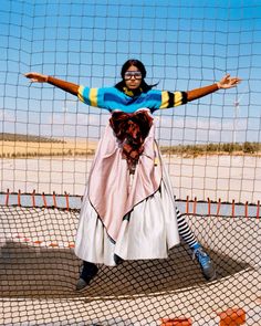 a woman is standing on one leg with her arms spread out in front of the net