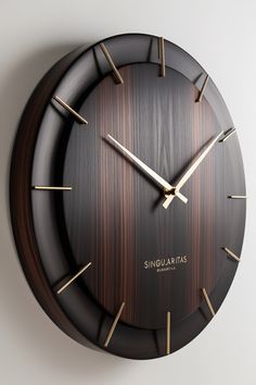 a black clock with gold hands on a white wall