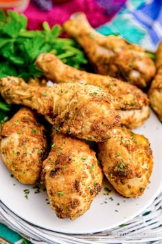 chicken wings on a white plate with greens and parsley in the backgroung