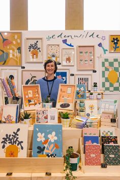 a woman standing in front of a table full of greeting cards and pictures on it