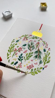 someone is painting a christmas ornament on paper