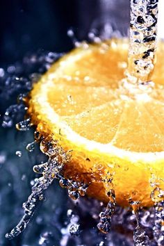 an orange being washed in water with a faucet