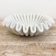 a white vase sitting on top of a wooden table